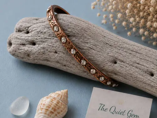 Pre-loved copper tone bangle bracelet with an etched floral design and clear rhinestone accents.