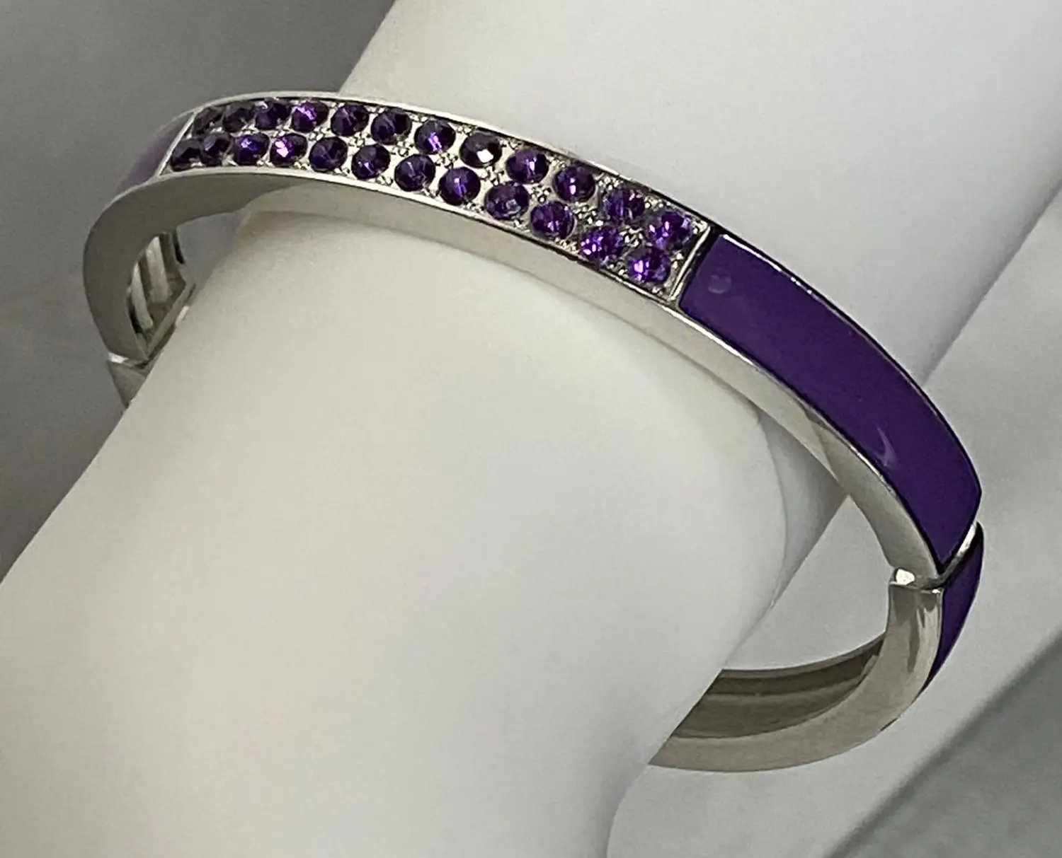 Retired Lia Sophia "Pop Rocks" silver tone fold-over stretch bracelet featuring glossy purple enamel and sparkling purple crystal accents displayed on a white jewelry stand.