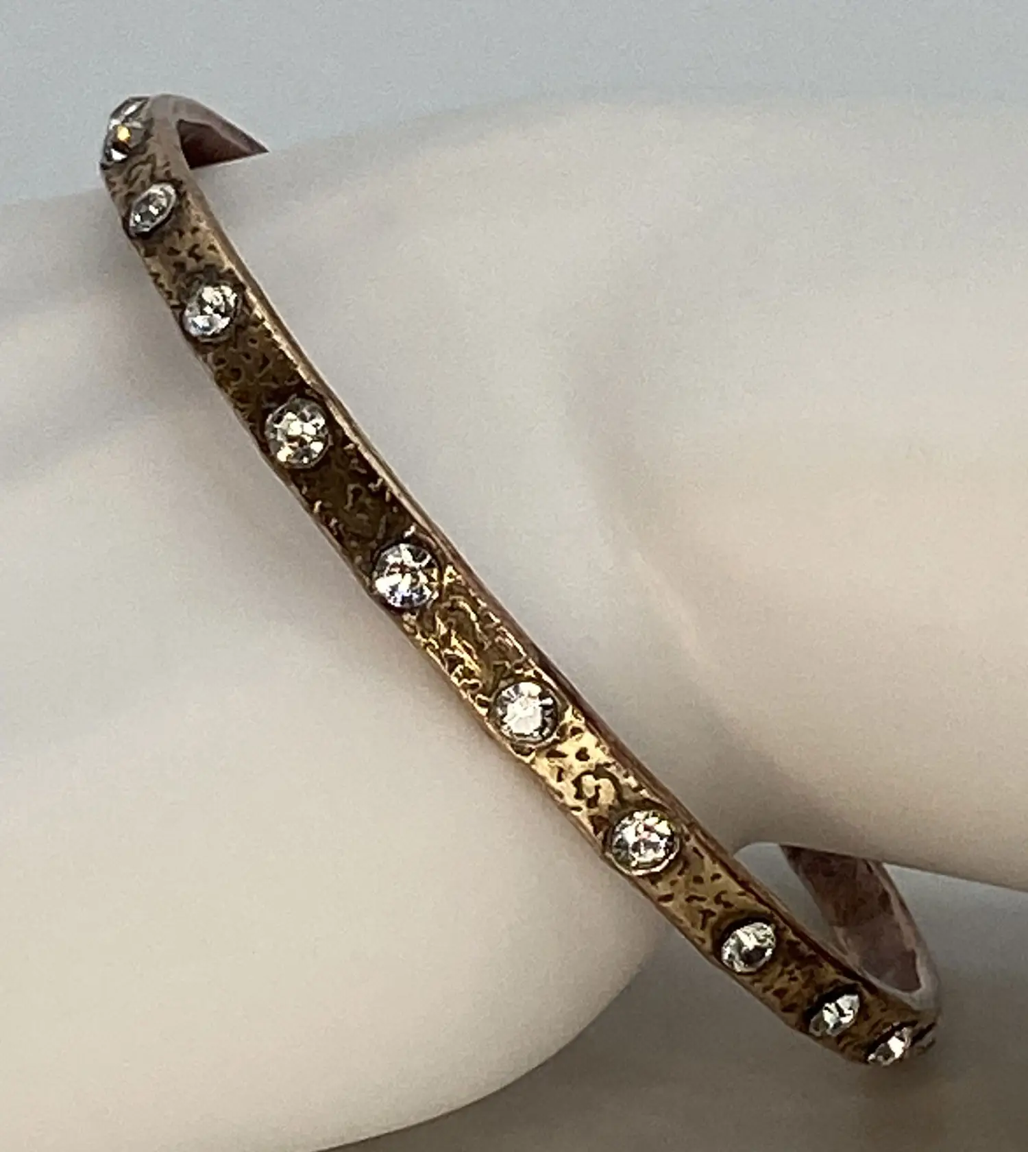 Pre-loved copper tone bangle bracelet with an etched floral design and clear rhinestone accents.