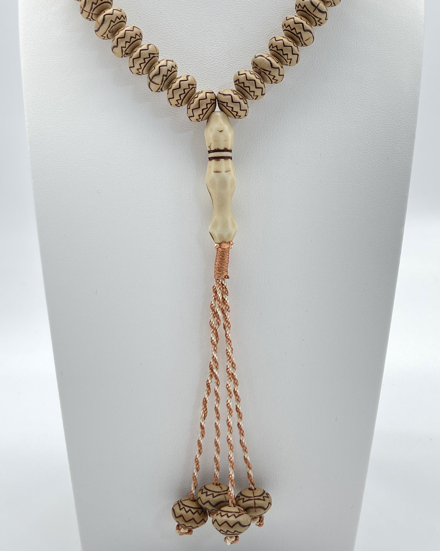 Pre-owned 99 prayer bead necklace with patterned natural-tone beads and long copper-tone tassel strands.
