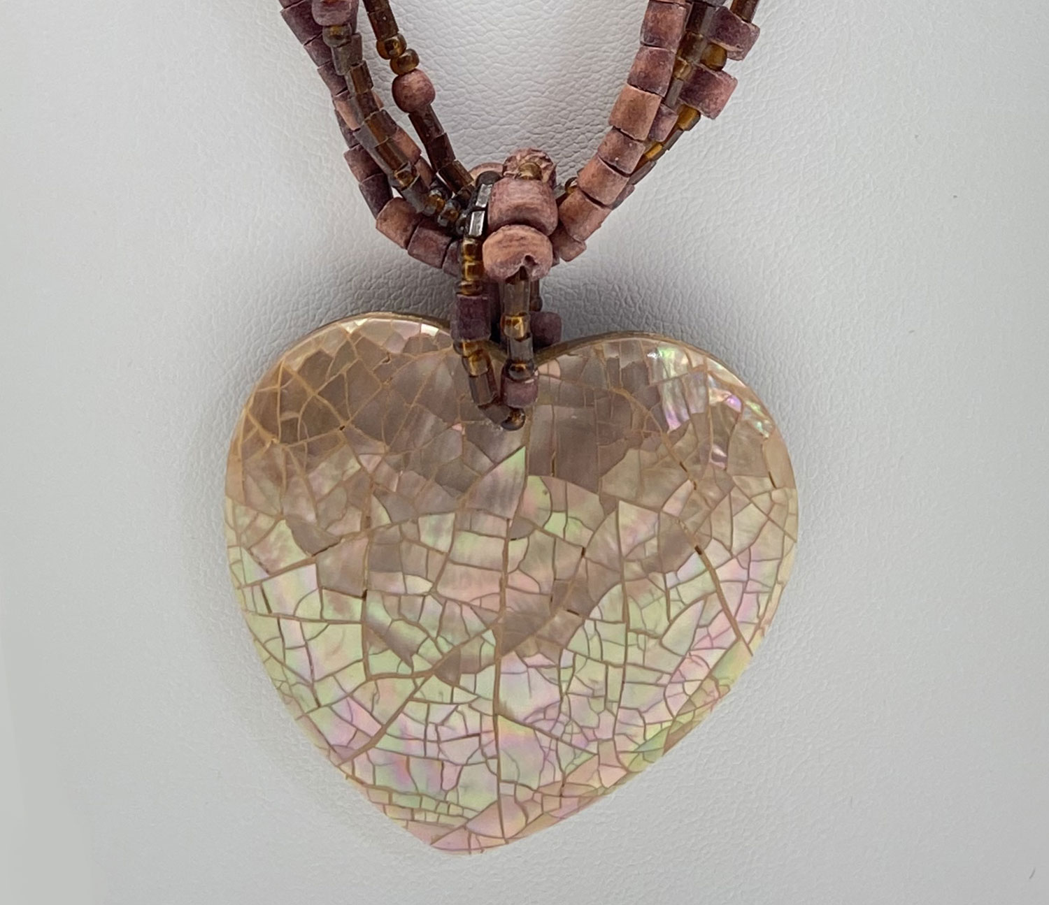 Pre-owned multi-strand wood beaded necklace with earthy brown beads and an iridescent mosaic Mother of Pearl heart pendant.