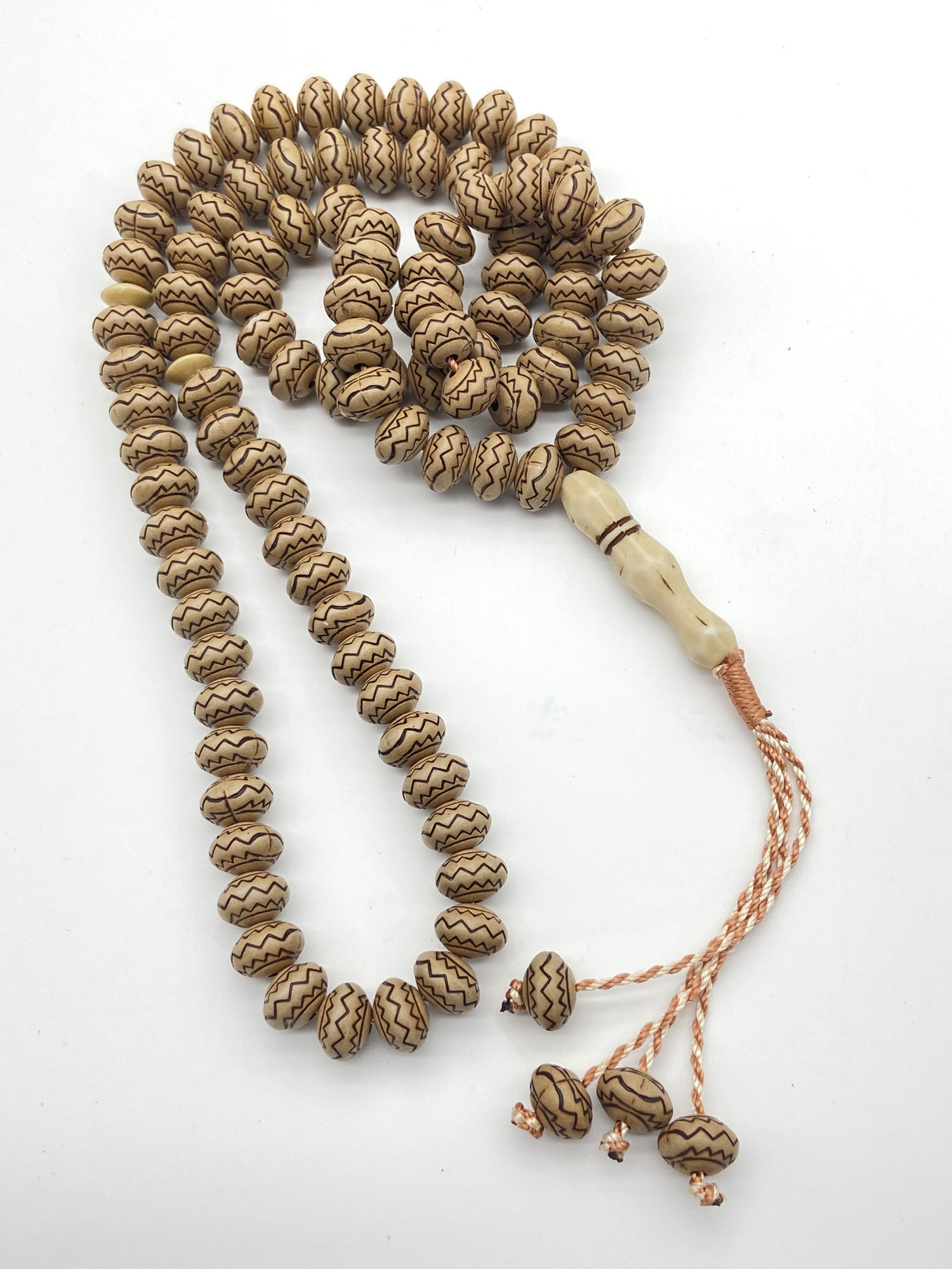 Pre-owned 99 prayer bead necklace with patterned natural-tone beads and long copper-tone tassel strands.