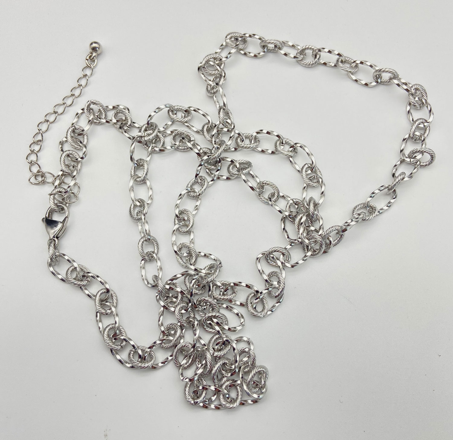 Upcycled silver tone layering chain necklace with matching link earrings displayed on a black jewelry bust
