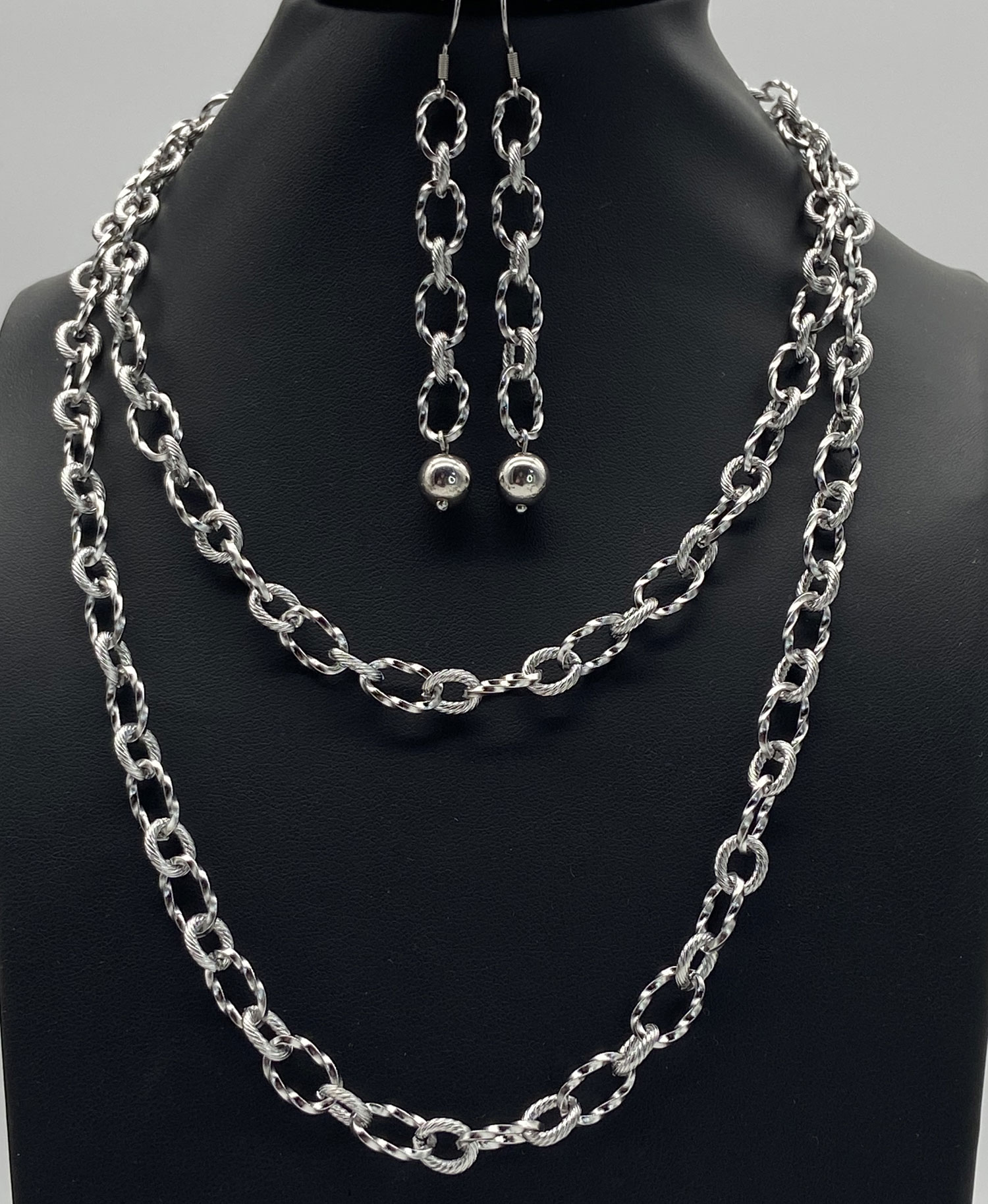 Upcycled silver tone layering chain necklace with matching link earrings displayed on a black jewelry bust