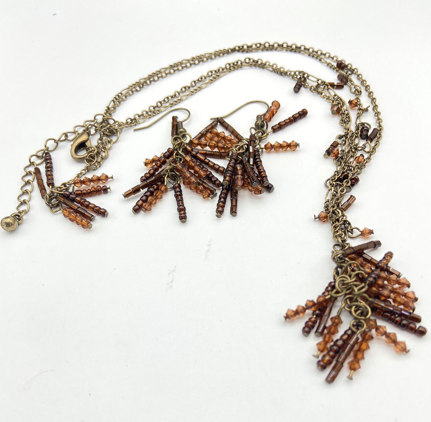 Pre-owned double-strand bronze-tone necklace and matching fringe earrings featuring amber-colored seed beads, displayed on a white background to show clasp