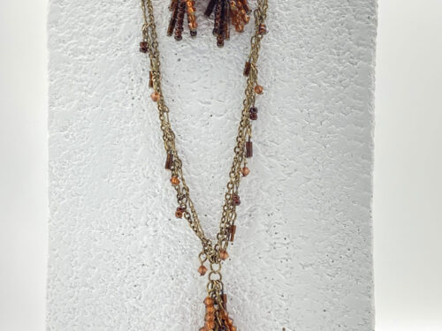 Pre-owned double-strand bronze-tone necklace and matching fringe earrings featuring amber-colored seed beads, displayed on a white jewelry bust.