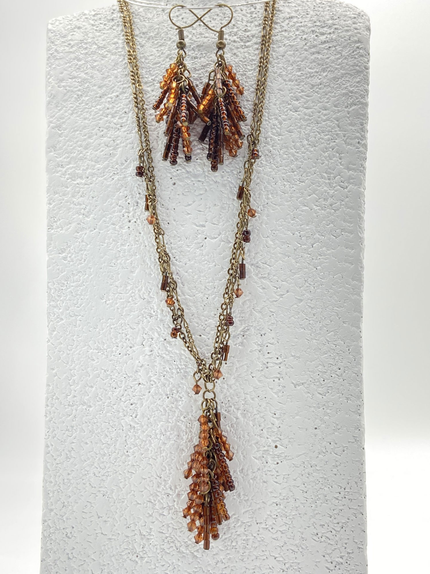 Pre-owned double-strand bronze-tone necklace and matching fringe earrings featuring amber-colored seed beads, displayed on a white jewelry bust.