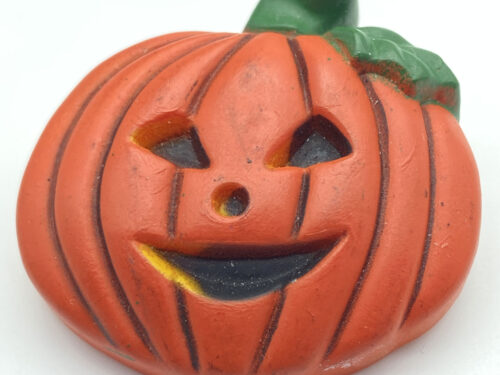 Vintage hand-painted orange resin pumpkin brooch with a smiling jack-o'-lantern face and green stem and leaves.