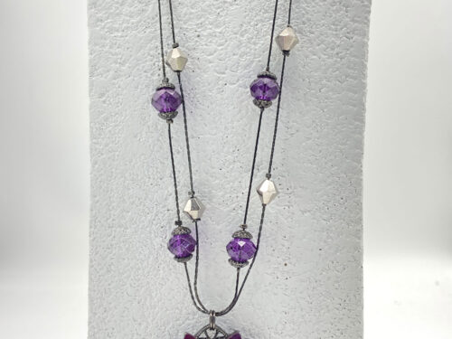 Purple Lucite flower pendant necklace with glittery petals, a faceted iridescent AB bead centre, purple accent beads, and a double-strand black chain.
