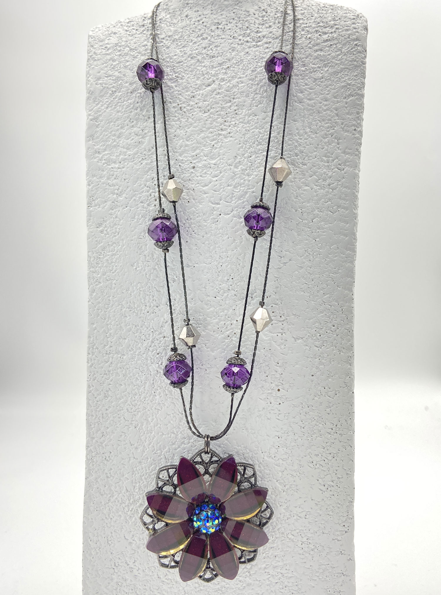 Purple Lucite flower pendant necklace with glittery petals, a faceted iridescent AB bead centre, purple accent beads, and a double-strand black chain.