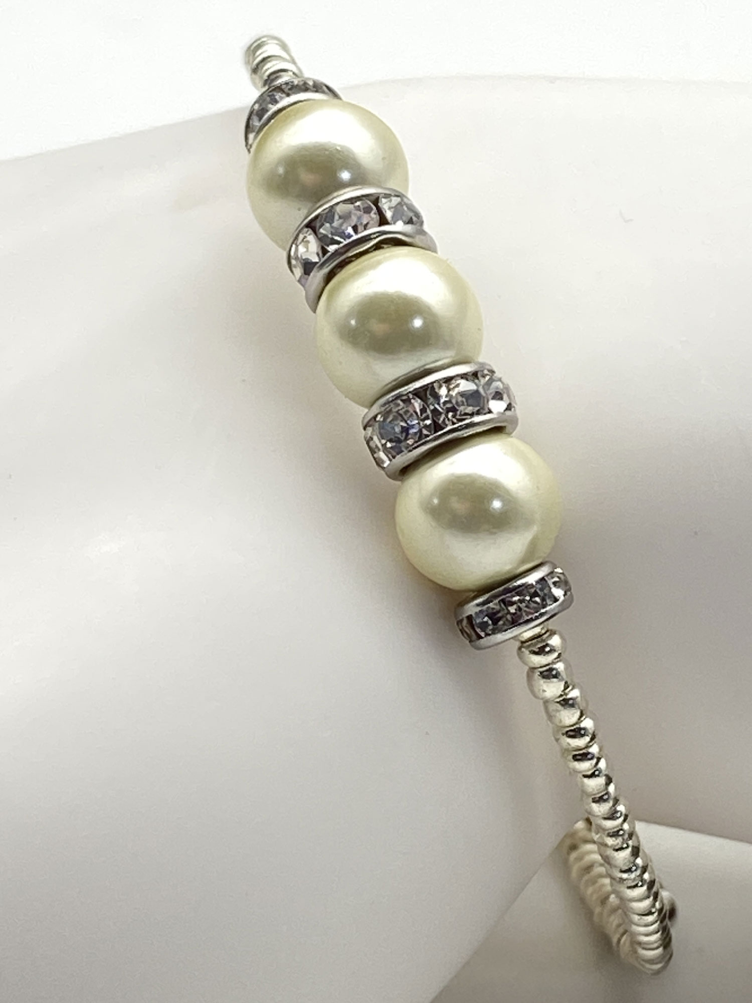Reimagined ivory faux pearl memory wire bracelet with rhinestone rondelles and silver-tone electroplated magnetic hematite beads.