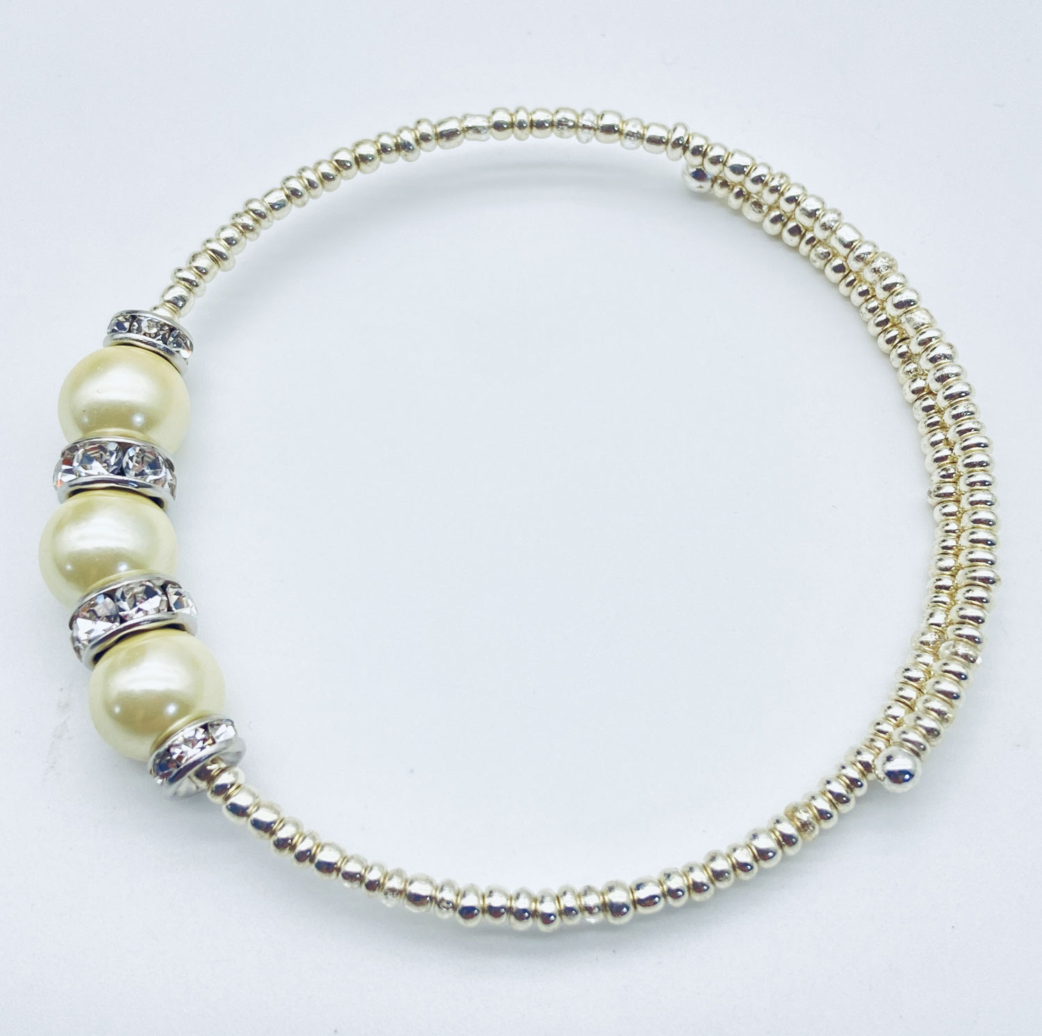 Reimagined ivory faux pearl memory wire bracelet with rhinestone rondelles and silver-tone electroplated magnetic hematite beads.
