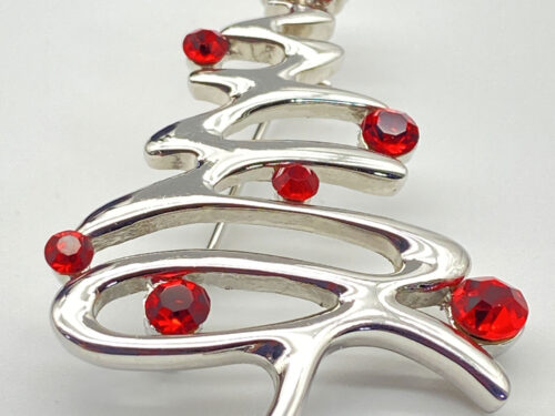 Vintage silver-tone Christmas tree brooch decorated with bright red rhinestones in a flowing openwork design.